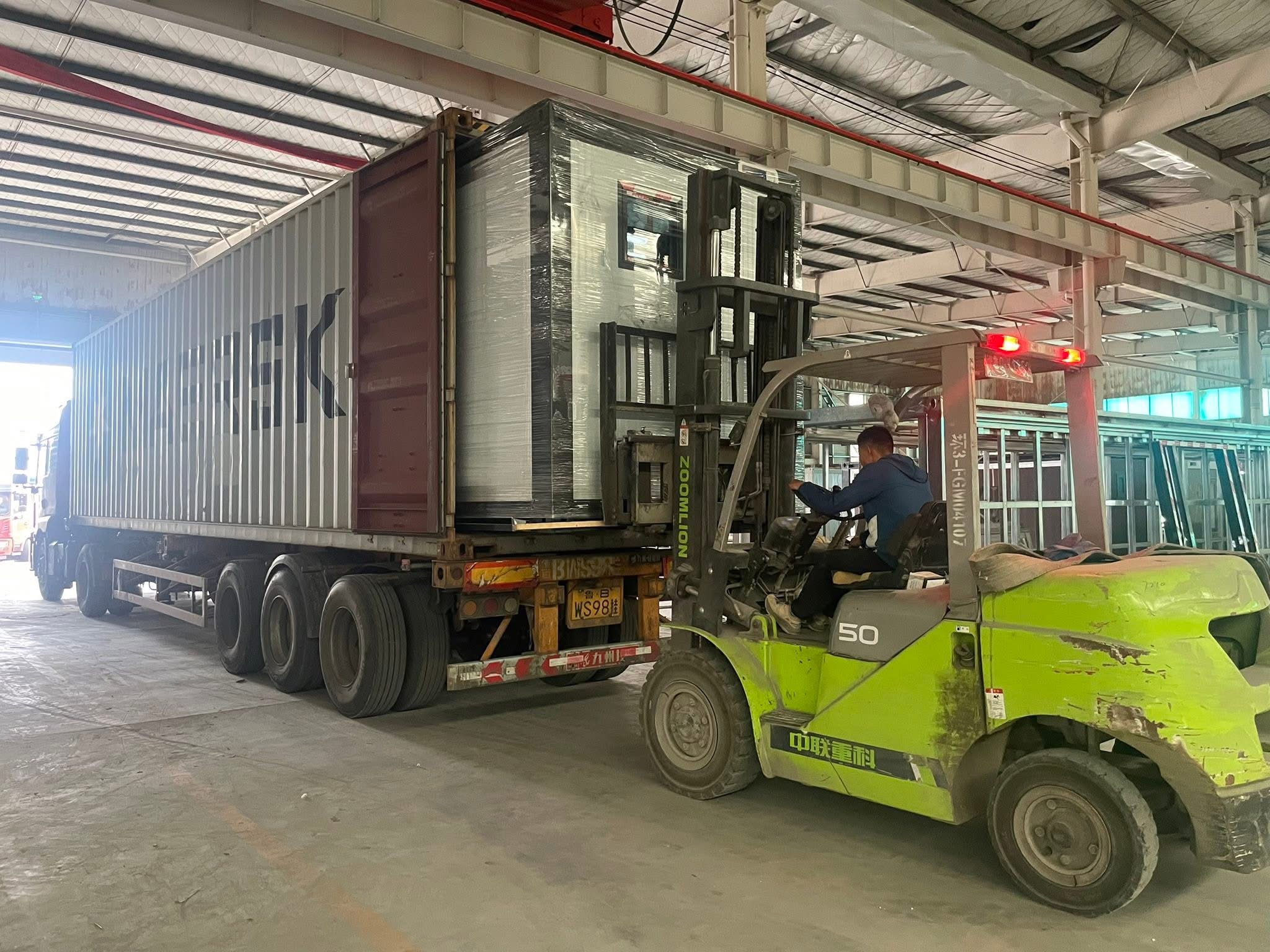 Outdoor kitchen module being loaded into a shipping container by forklift